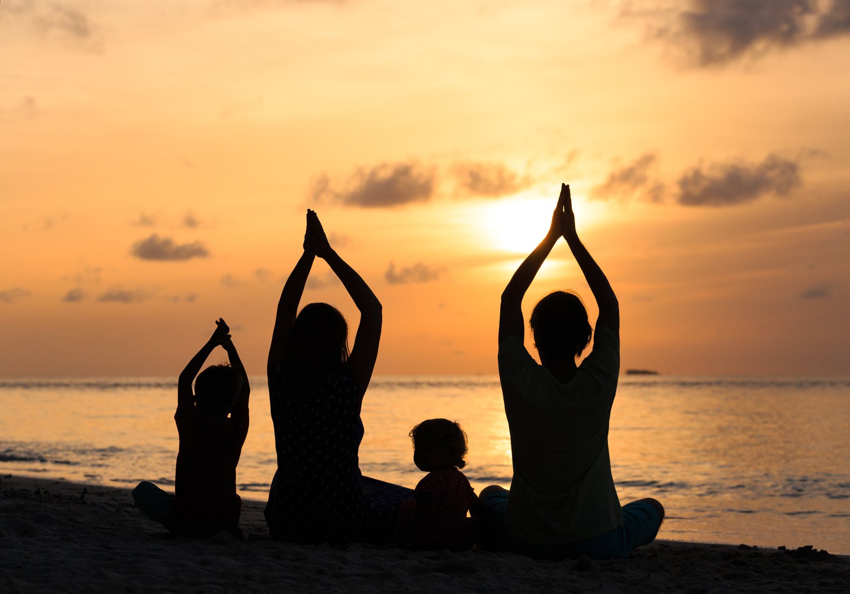 family silhouettes doing yoga at sunset